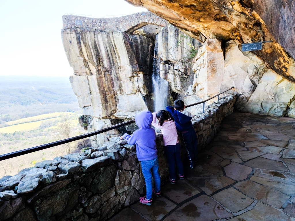 Three children standing in front of the waterfall at Rock City on Lookout Mountain